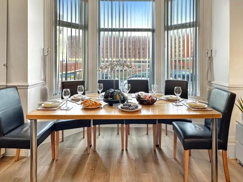 a dining room table with chairs and wine glasses at Granada Apartments Derby Road in Blackpool