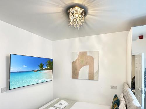 a living room with a tv and a chandelier at Granada Apartments Derby Road in Blackpool