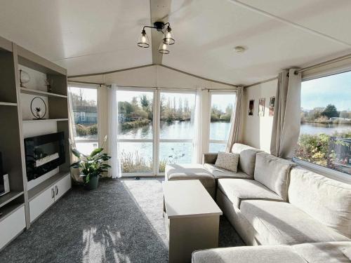 a living room with a couch and large windows at Billing Aquadrome - Bird Lake View in Great Billing
