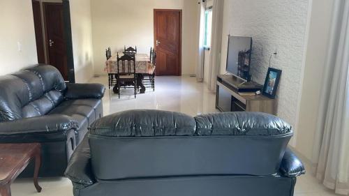 a living room with a leather couch and a table at Casa temporada em Perocão in Guarapari