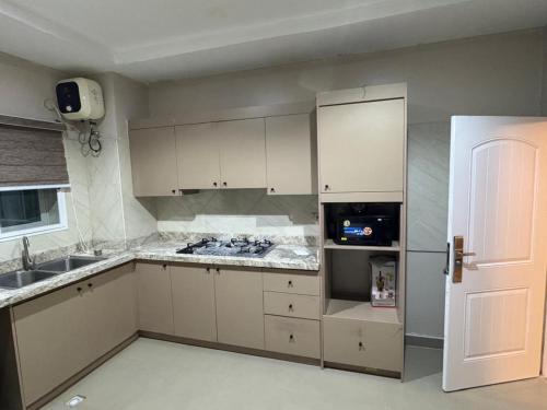 a kitchen with white cabinets and a white refrigerator at Epic Apartment in Abuja
