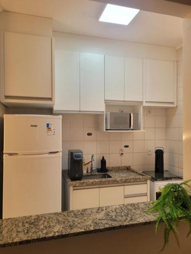 a kitchen with white cabinets and a white refrigerator at Rê apdetemporadas em Olímpia 63 piscina, WI FI, próximo do Termas O MELHOR P SUA FAMILIA in Olímpia