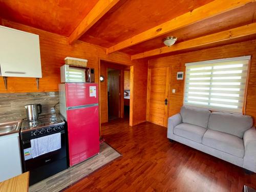 a kitchen with a red refrigerator and a couch in a room at Cabaña Canelita in Cochrane
