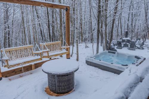 una vasca idromassaggio nella neve accanto a due panchine di Kos - Domaine du Grand Portneuf - Spa Nature & Comfort a Pont-Rouge