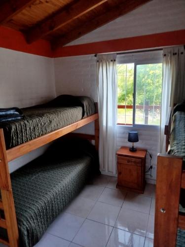 a bedroom with two bunk beds and a window at Cabañas del Puente - Rio Grande San Luis in La Bajada