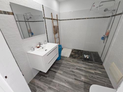 ein Badezimmer mit einem weißen Waschbecken und einer Dusche in der Unterkunft Tropikaz in Le Diamant