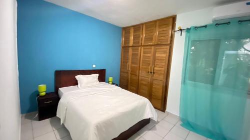 ein Schlafzimmer mit einem Bett und einer blauen Wand in der Unterkunft Les Jardins Prives Odza in Jaunde
