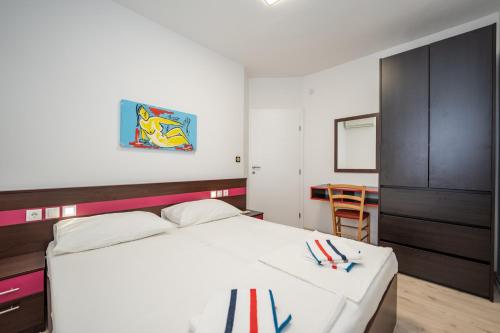 a bedroom with a white bed and a black cabinet at Apartments Dvori Novalja in Novalja