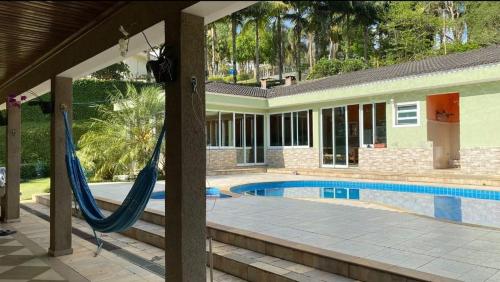 eine Hängematte vor einem Haus mit Pool in der Unterkunft Chácara Recanto dos Lagos in Cotia