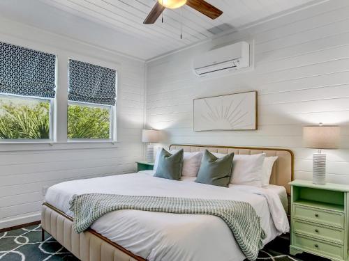 a white bedroom with a bed and two windows at Beachside Villa Unit 5 in Tybee Island