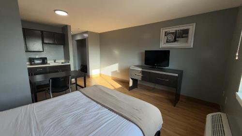 ein Schlafzimmer mit einem Bett und einem Schreibtisch mit einem Fernseher in der Unterkunft Welcome Suites Hazelwood Extended Stay Hotel in Hazelwood