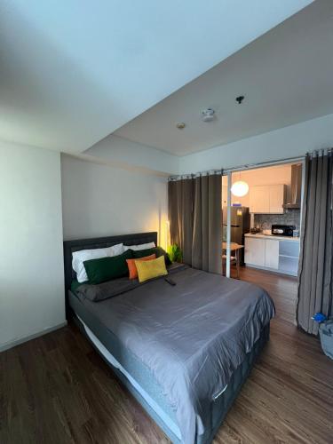 a bedroom with a large bed and a kitchen at Pixel Studio - Azure Residences Staycation in Sampong