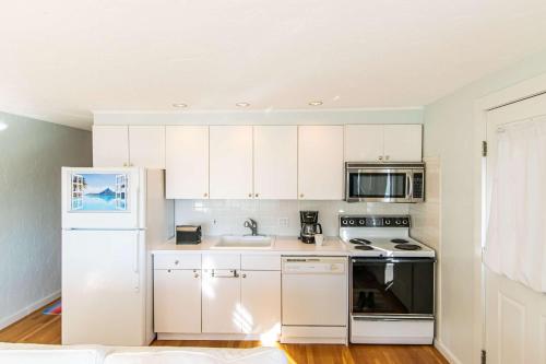 a kitchen with white cabinets and a white refrigerator at East End Condo Across from Assoc Beach in Provincetown
