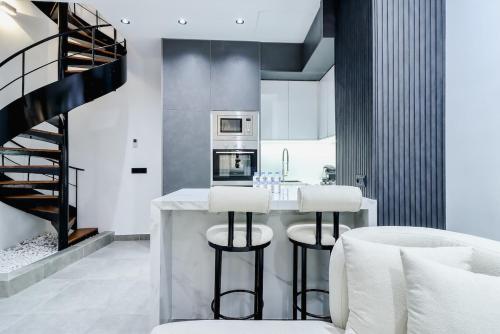 Oulad AkkouにあるLoft N 38, Cherifiaのスツールと階段付きのバーのあるキッチン