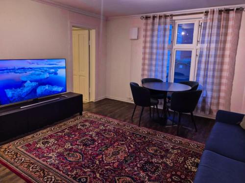 un salon avec une télévision, une table et des chaises dans l'établissement Cozy 2BD apartment in Central Bergen, à Bergen