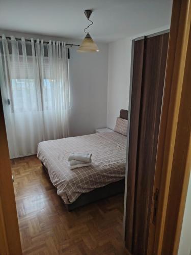 a small bedroom with a bed and a window at Sicilija apartment in Podgorica