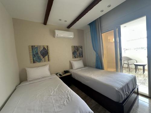 two beds in a room with a window at Giza Pyramids Inn in Cairo