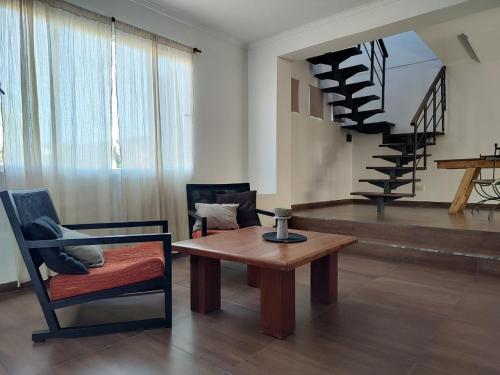 a living room with a table and a spiral staircase at Hornero House in San Antonio de Areco