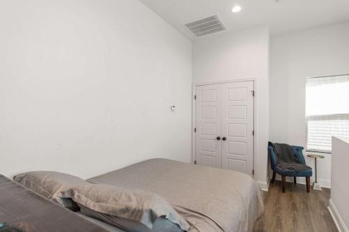 a white bedroom with a bed and a blue chair at Charming Townhome - New Construction in Lafayette