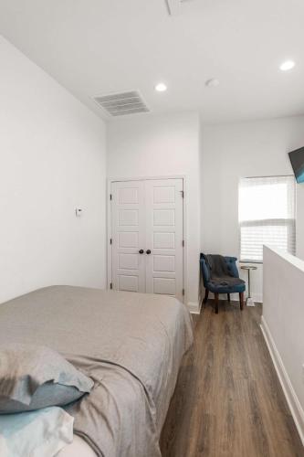 a white bedroom with a bed and a blue chair at Charming Townhome - New Construction in Lafayette