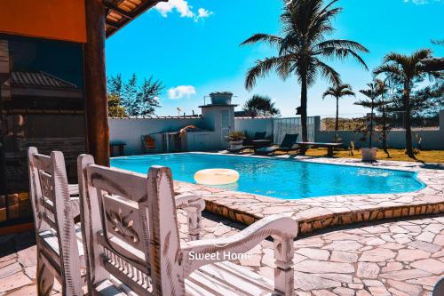 - une piscine avec 2 chaises en face d'une maison dans l'établissement Pousada Sweet Home, à Búzios
