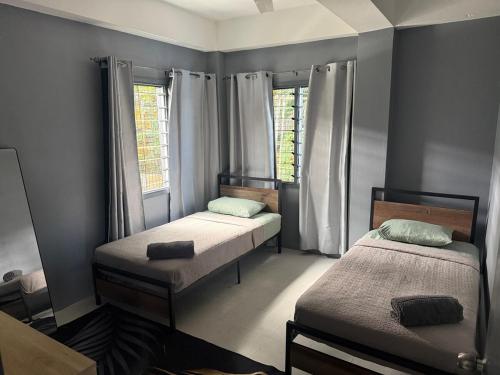 a bedroom with two beds and two windows at The Athaliah Abode in Suva