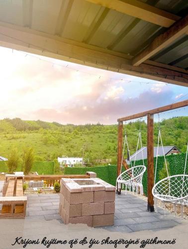 a patio with two swings and a table and benches at Villa Konezal in Ferizaj