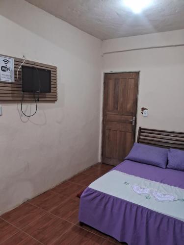- une chambre avec un lit violet et une télévision dans l'établissement Recanto feliz, à São Thomé das Letras