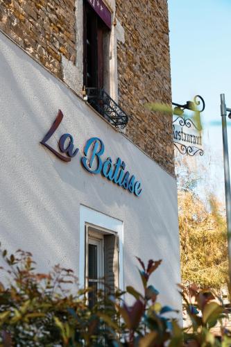 a sign on the side of a building with a window at Hôtel La Batisse in Crémieu