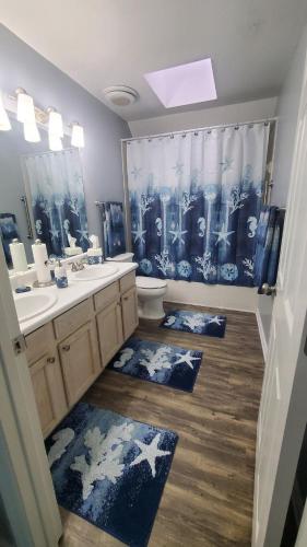 a bathroom with two sinks a toilet and a shower curtain at Jenkins Cove Getaway in Tybee Island