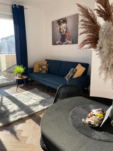 a living room with a blue couch and a table at Ami Luxury Residence XII CENTRUM - możliwość REJSU ŁODZIĄ in Iława