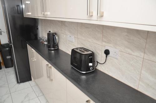 a kitchen counter with a toaster plugged into a outlet at JMG HOUSE - Quality Rooms in West Bromwich