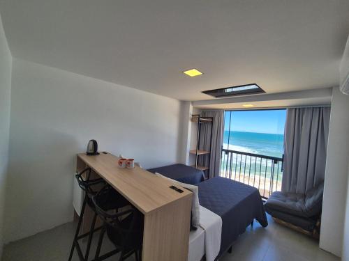 a room with a bed and a desk and a balcony at Hibisco Guest House in Florianópolis