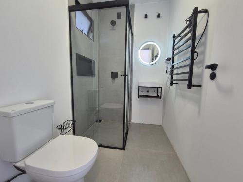 a bathroom with a toilet and a glass shower at Hibisco Guest House in Florianópolis