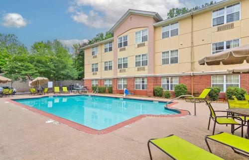 a swimming pool with tables and chairs in front of a building at Extended Stay America Suites - Atlanta - Alpharetta - Northpoint - West in Alpharetta