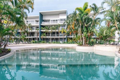 a swimming pool in front of a building with palm trees at Luxury Spacious 3 Bedroom Apartment - Gold Coast in Gold Coast