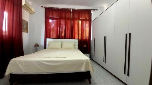 1 dormitorio con 1 cama grande y cortinas rojas en Central Apartments Shoshi, en Tirana