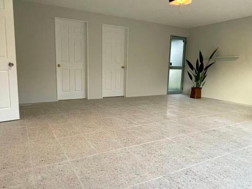 an empty room with two white doors and a potted plant at 2 Bedroom Cozy Space Near Botany in Auckland