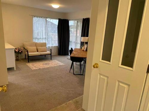 a living room with a table and a chair and a door at 2 Bedroom Cozy Space Near Botany in Auckland