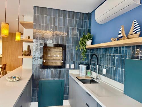 a kitchen with blue tiled walls and a sink at Apartamento 3 dormitórios quadra da praia in Balneário Camboriú