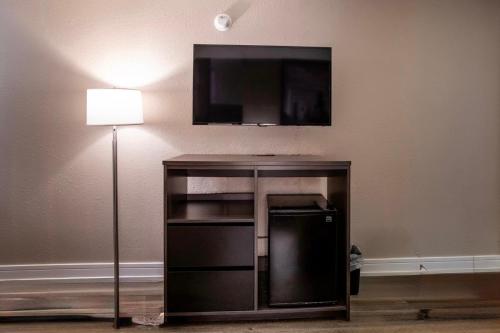 a flat screen tv on a wall next to a lamp at Super 8 by Wyndham Rockford South in Rockford