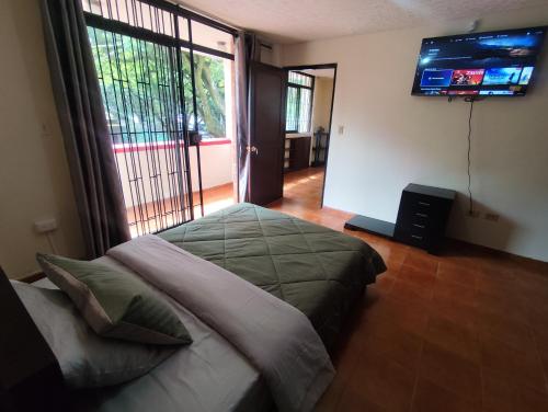 a bedroom with a bed and a television on the wall at Casa de hospedaje Lili - Cali in Cali