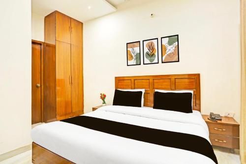 a bedroom with a large white bed and a wooden headboard at Super Hotel O Sector 45 Formerly Manyavar in Chandīgarh