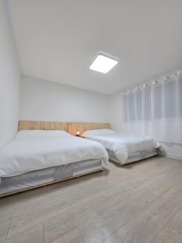 two beds in a bedroom with white walls at Haven 10 HOUSE in Seoul