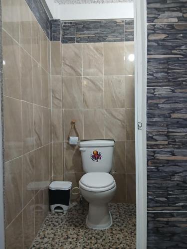 a bathroom with a toilet and a tile wall at Hostal in Sontecomapan