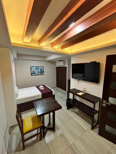 a living room with a television and a table at Hotel Framfor Inn Chetumal in Chetumal