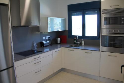 eine Küche mit weißen Schränken und einer Spüle und einem Fenster in der Unterkunft Las Olas Denia in Denia