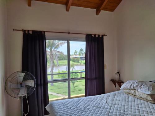 a bedroom with a bed and a fan and a window at La casa del lago in Oliveros