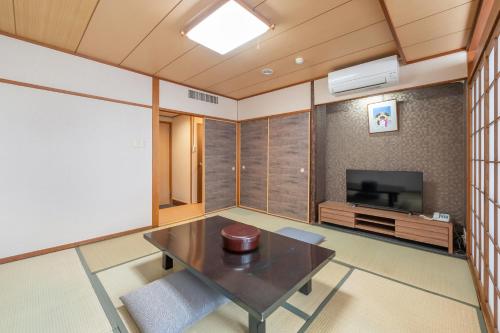 a room with a table and a flat screen tv at Subaruyado Yoshino in Tokushima