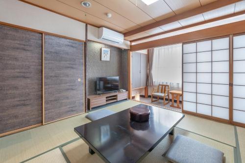 a living room with a table and a tv at Subaruyado Yoshino in Tokushima